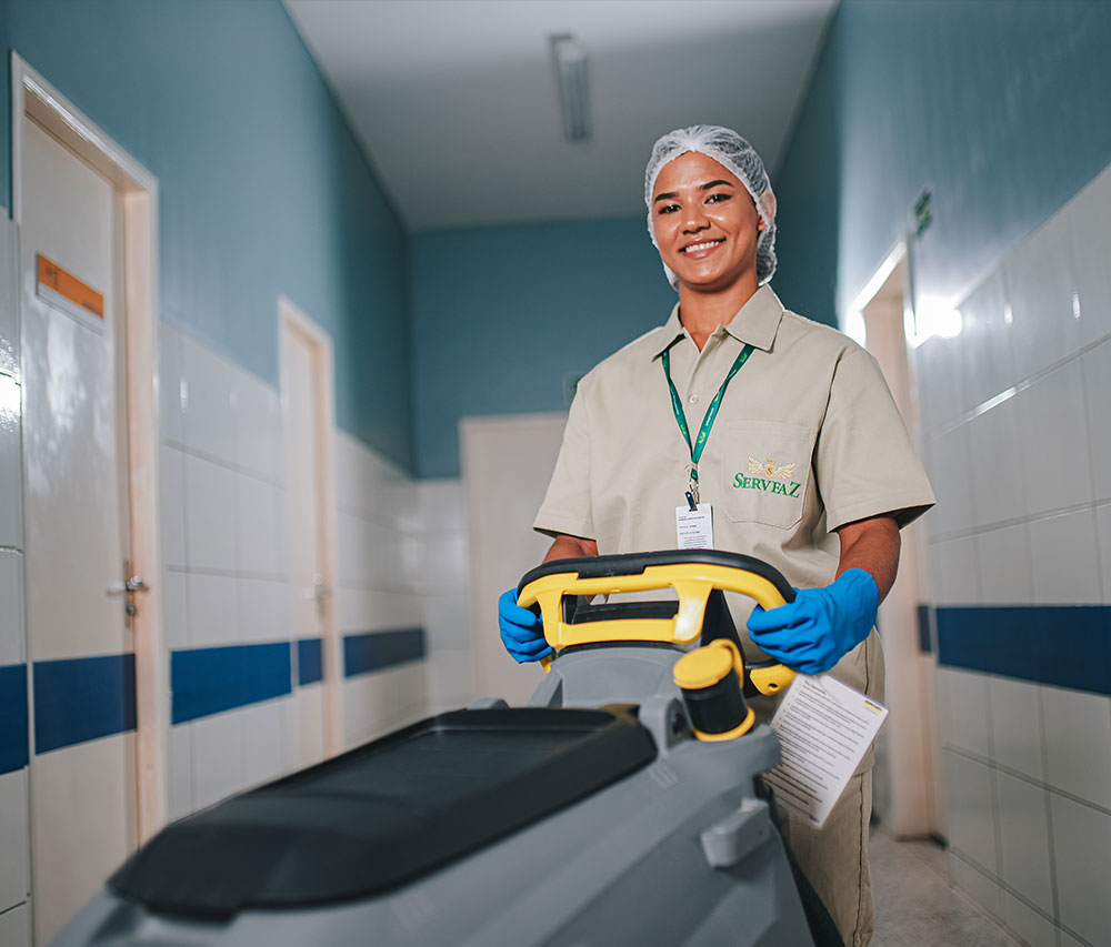 colaboradora da servfaz sorrindo e utilizando um equipamento de limpeza